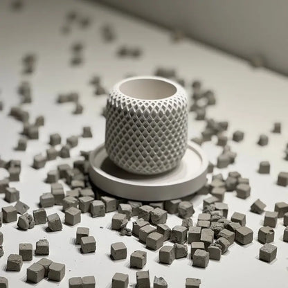 White textured cylindrical object surrounded by small gray cubes on a light surface.