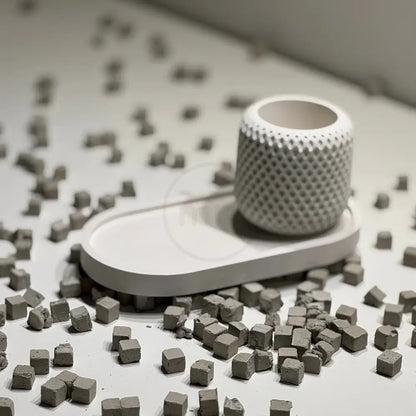 White textured object on a white surface with scattered small gray cubes